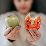 Woman showing apple and bitten doughnut